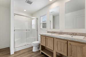 Bathroom featuring hardwood / wood-style floors, vanity, toilet, and a shower with shower door