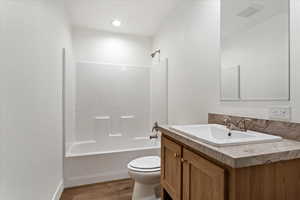 Full bathroom featuring vanity, wood-type flooring,  shower combination, and toilet