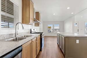 Kitchen with appliances with stainless steel finishes, sink, light brown cabinets, wood-type flooring, and a center island