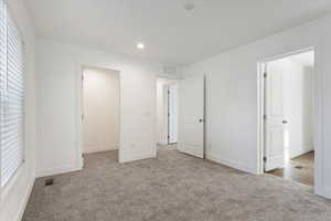 Unfurnished bedroom featuring light carpet, a spacious closet, and a closet