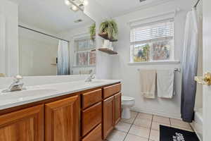 Full bathroom with tile patterned floors, shower / bathtub combination with curtain, vanity, and toilet