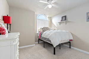 Bedroom featuring a textured ceiling, light colored carpet, and ceiling fan