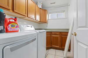 Laundry room with cabinets, washer and dryer, and light tile patterned flooring