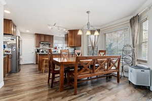 Dining space featuring hardwood / wood-style floors, a healthy amount of sunlight, crown molding, and an inviting chandelier