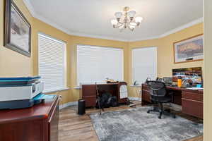 Office space with ornamental molding, light wood-type flooring, and an inviting chandelier