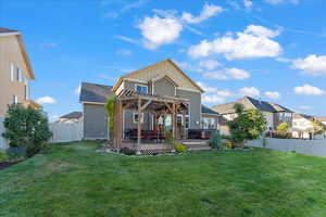 Back of property featuring a pergola, a yard, a wooden deck, and a hot tub