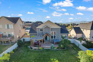 Back of house with a yard, a wooden deck, and a hot tub