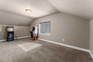 Additional living space with carpet flooring, a textured ceiling, and vaulted ceiling