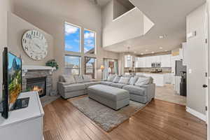 Living room featuring light hardwood / wood-style floors, a fireplace, and a high ceiling