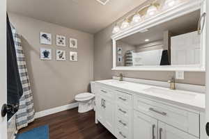 Bathroom featuring hardwood / wood-style flooring, vanity, toilet, and a shower with shower curtain