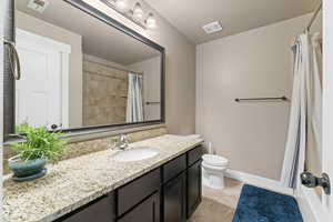 Bathroom with a shower with curtain, vanity, and toilet