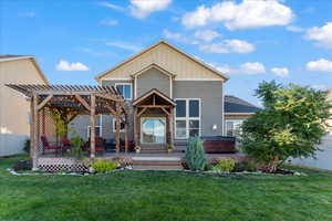 Back of house with a pergola, a hot tub, a deck, and a lawn