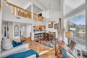 Living room with beamed ceiling, ceiling fan, light hardwood / wood-style floors, and high vaulted ceiling