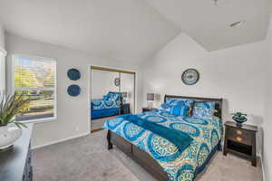 Carpeted bedroom featuring a textured ceiling, vaulted ceiling, and a closet