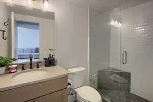 Bathroom featuring vanity, toilet, and an enclosed shower