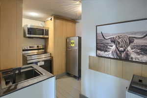 Kitchen with sink, stainless steel appliances, light brown cabinets, and light wood-type flooring