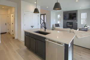 Kitchen with dishwasher, pendant lighting, a center island with sink, and light hardwood / wood-style floors