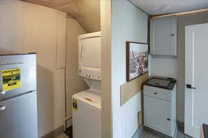 Washroom featuring light tile patterned floors and stacked washer and clothes dryer