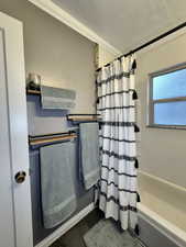 Bathroom featuring crown molding and shower / bathtub combination with curtain