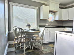 Kitchen featuring white cabinets, crown molding, and sink