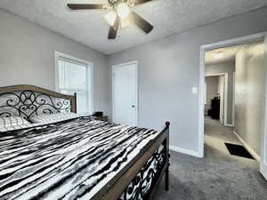 Bedroom featuring dark colored carpet, a textured ceiling, and ceiling fan