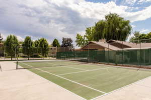 View of tennis court featuring basketball hoop