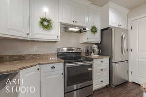 Kitchen featuring white cabinetry, dark hardwood / wood-style flooring, stainless steel appliances, and light stone counters