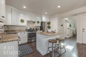 Kitchen featuring a kitchen island, dark hardwood / wood-style flooring, white cabinetry, and appliances with stainless steel finishes