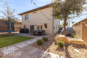 Rear view of house with a patio area, a yard, and a trampoline