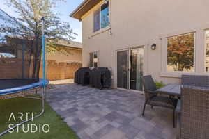 View of patio with a trampoline and area for grilling