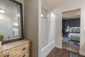 Bathroom featuring hardwood / wood-style flooring, vanity, shower / bathtub combination with curtain, and a textured ceiling