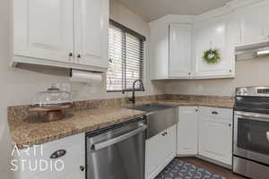 Kitchen with dark hardwood / wood-style floors, white cabinets, stainless steel appliances, and extractor fan