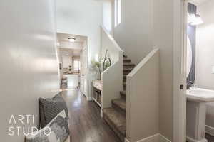 Stairs featuring wood-type flooring, a healthy amount of sunlight, and sink