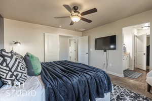 Bedroom with hardwood / wood-style floors, connected bathroom, a textured ceiling, and ceiling fan