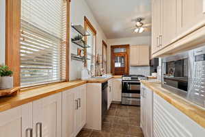 Kitchen featuring dark tile patterned flooring, sink, ceiling fan, appliances with stainless steel finishes, and butcher block countertops