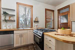 Kitchen with plenty of natural light, sink, appliances with stainless steel finishes, and wooden counters