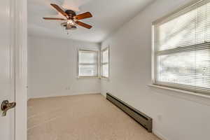 Spare room with ceiling fan, plenty of natural light, and a baseboard radiator