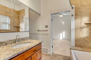 Bathroom featuring vanity, ceiling fan, and a tub to relax in