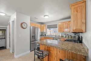 Kitchen with sink, stainless steel appliances, kitchen peninsula, a textured ceiling, and a kitchen bar