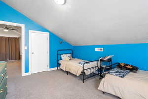 Carpeted bedroom featuring a textured ceiling and vaulted ceiling