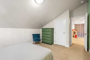 Carpeted bedroom featuring a textured ceiling and lofted ceiling