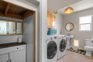 Washroom featuring washer and dryer, light tile patterned floors, and sink