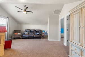 Living room with ceiling fan, light colored carpet, and lofted ceiling