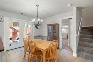 Tiled dining area featuring french doors and a chandelier