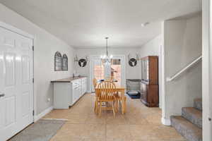 Tiled dining room with french doors, a chandelier, and a textured ceiling