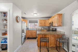 Kitchen with a kitchen breakfast bar, light tile patterned floors, kitchen peninsula, and appliances with stainless steel finishes