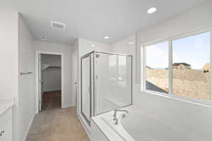 Bathroom featuring vanity, tile patterned flooring, and plus walk in shower