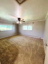 Carpeted empty room featuring ceiling fan, crown molding, and a baseboard radiator