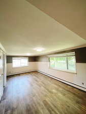 Interior space featuring plenty of natural light, wood-type flooring, and a baseboard radiator