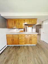 Kitchen featuring white fridge, light hardwood / wood-style floors, kitchen peninsula, and baseboard heating